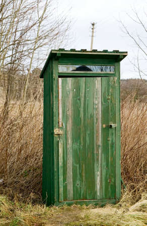 Green outdoor toilet near the field, unsanitary concept village