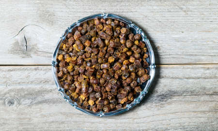 Propolis granules inside plate on wooden background, bee productの写真素材
