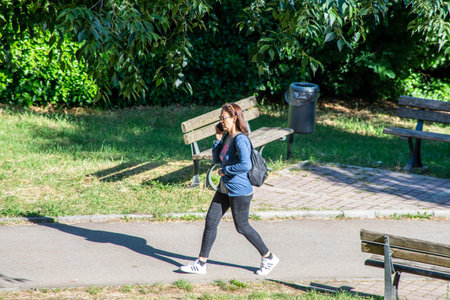 terni,italy june 01 2020 :girl at park strolling with smatphone in the morningのeditorial素材