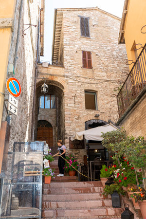 assisi,italy july 11 2020:a woman watering her plants in an alley in Assisiのeditorial素材