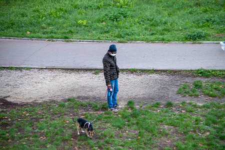terni, italy actober 10 2020: a man in the park with his dog doing needs with a medical maskのeditorial素材