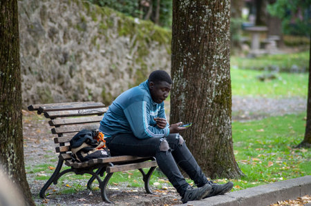 terni, italy october 13 2020: black man sitting on a bench at the parkのeditorial素材