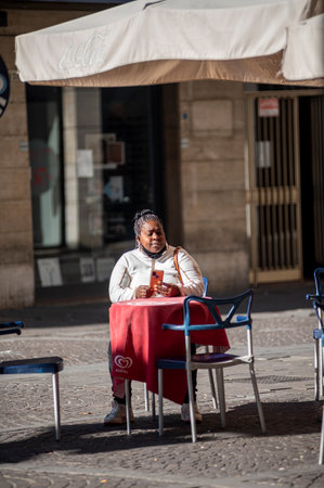 terni, italy october 21 2020: black woman sitting at a table in an outdoor cafeのeditorial素材