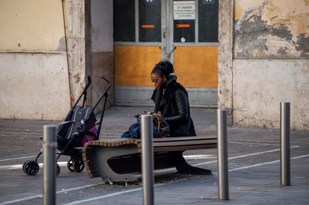 terni, italy october 21 2020: black woman sitting on a bench with a small strollerのeditorial素材