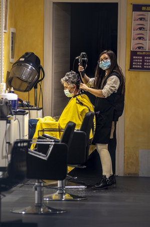 terni, italy september 02 2020: hairdresser who gives hair to a client with medical masksのeditorial素材