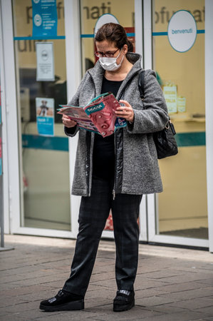 terni, itali november 05 2020: elderly oriental woman with medical mask sitting on a bench on the phoneのeditorial素材