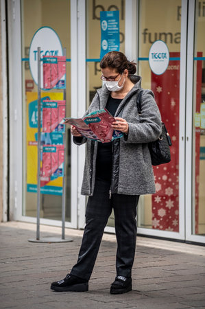 terni, itali november 05 2020: elderly oriental woman with medical mask sitting on a bench on the phoneのeditorial素材