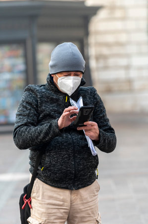 terni.italy jenuary 30 2021:man with medical mask watching smartphone in the cityのeditorial素材