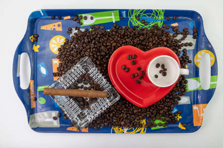 composition of coffee beans with heart shaped cup and saucer with ashtray and cigarの写真素材