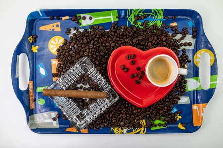 composition of coffee beans with heart shaped cup and saucer with ashtray and cigarの写真素材