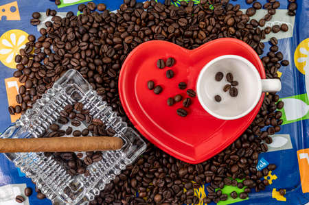composition of coffee beans with heart shaped cup and saucer with ashtray and cigarの写真素材