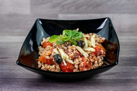 served on black plate of farroset salad on wooden tableの写真素材