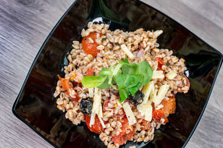 served on black plate of farroset salad on wooden tableの写真素材