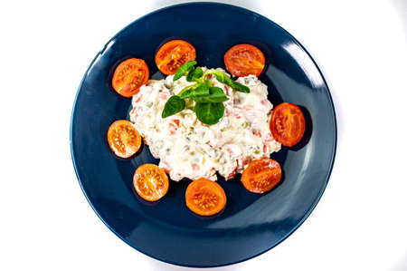 Russian salad on blue plate with cherry tomatoes on white backgroundの写真素材