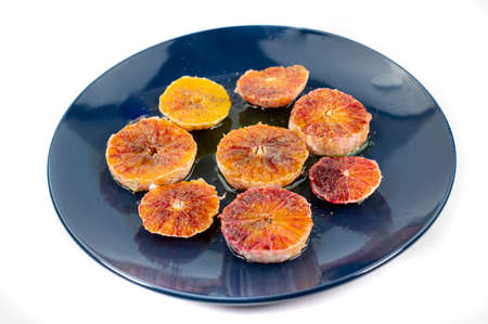 oranges seasoned with oil salt and pepper on a blue plate and wooden background orangesの写真素材