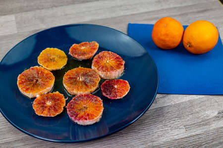 oranges seasoned with oil salt and pepper on a blue plate and wooden background orangesの写真素材