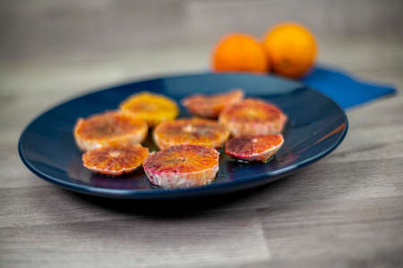 oranges seasoned with oil salt and pepper on a blue plate and wooden background orangesの写真素材