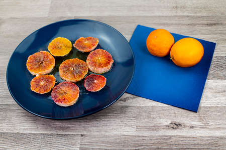 oranges seasoned with oil salt and pepper on a blue plate and wooden background orangesの写真素材