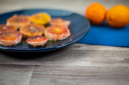 oranges seasoned with oil salt and pepper on a blue plate and wooden background orangesの写真素材