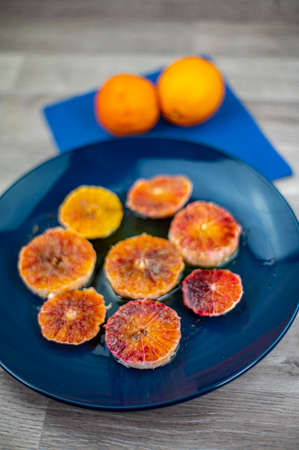 oranges seasoned with oil salt and pepper on a blue plate and wooden background orangesの写真素材