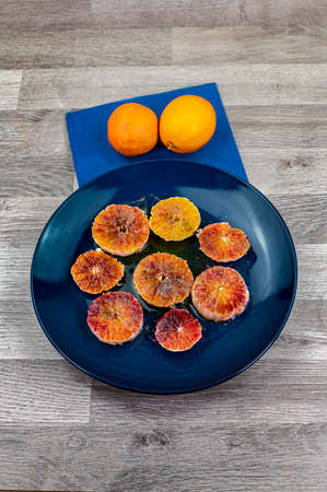 oranges seasoned with oil salt and pepper on a blue plate and wooden background orangesの写真素材