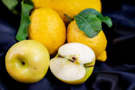 yellow fruit on a black background with melon bananas apples and lemonsの写真素材