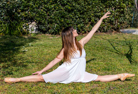 ballerina in various poses in nature environment with white dress and pointe shoesの写真素材