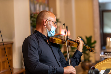 terni, italy may 20 2021: violinist in church with medical mask playing violinのeditorial素材