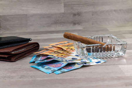 20 and 50 euro banknotes and wallet and cigar on wood backgroundの写真素材