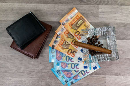20 and 50 euro banknotes and wallet and cigar on wood backgroundの写真素材
