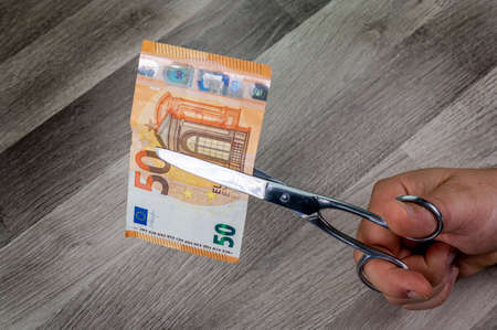 cut 50 euro banknotes with scissors on wooden tableの写真素材