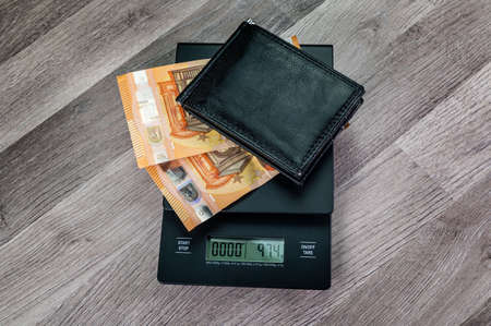 euro banknotes on top of a scale with portafolio on a wooden tableの写真素材