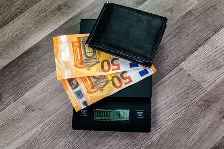 euro banknotes on top of a scale with portafolio on a wooden tableの写真素材