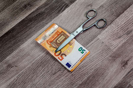 cut 50 euro banknotes with scissors on wooden tableの写真素材