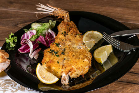 monkfish au gratin plate with composition on wooden top and wine glass and cutleryの写真素材
