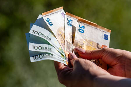 banknotes of 50 and 100 euros in the hands of a woman background in natureの写真素材