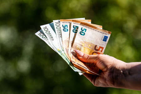 banknotes of 50 and 100 euros in the hands of a woman background in natureの写真素材