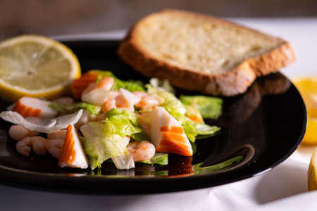 composition of a black plate with shrimp and surimi salad on a white satin backgroundの写真素材