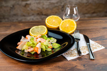 composition of a black plate with shrimp and surimi salad on a white satin backgroundの写真素材