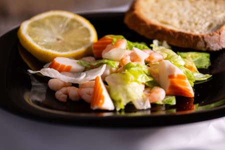 composition of a black plate with shrimp and surimi salad on a white satin backgroundの写真素材