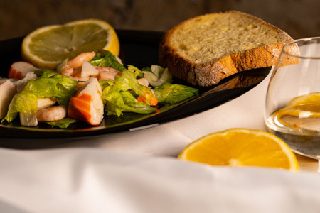 seafood salad composition with shrimps and surimi with cutlery and glass of white wine and lemonsの写真素材