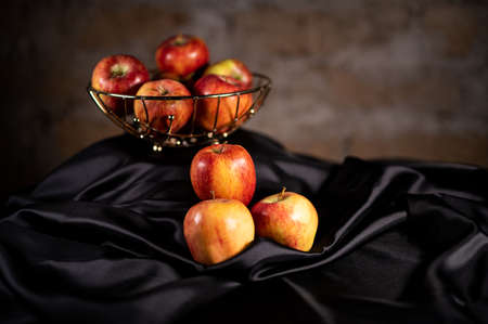 apples in golden basket on wooden countertopの写真素材