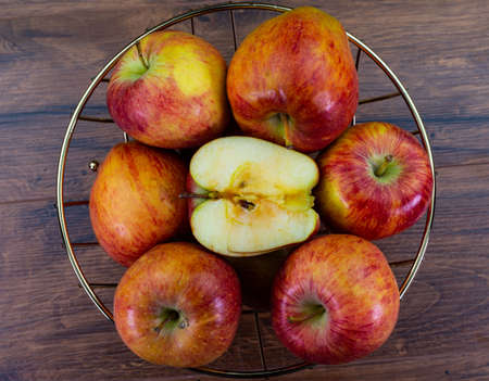 apples in golden basket on wooden countertopの写真素材