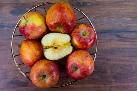 apples in golden basket on wooden countertopの写真素材