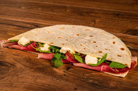 composition of sandwiches with salami and vegetables on a wooden surfaceの写真素材