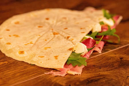 composition of sandwiches with salami and vegetables on a wooden surfaceの写真素材