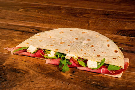 composition of sandwiches with salami and vegetables on a wooden surfaceの写真素材
