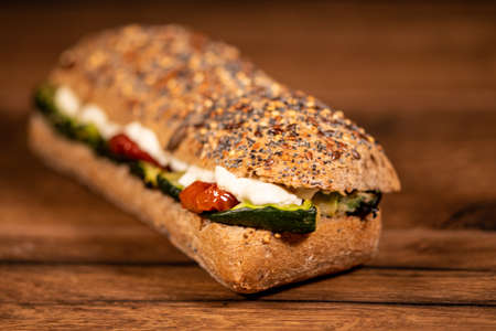 sandwich with salami and vegetables on a wooden surfaceの写真素材