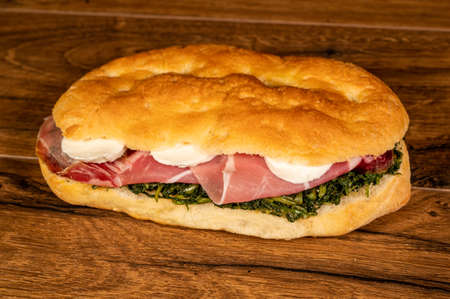 sandwich with salami and vegetables on a wooden surfaceの写真素材