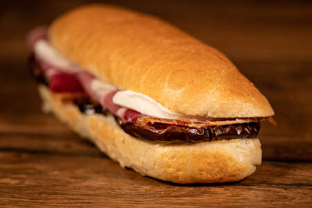 sandwich with salami and vegetables on a wooden surfaceの写真素材